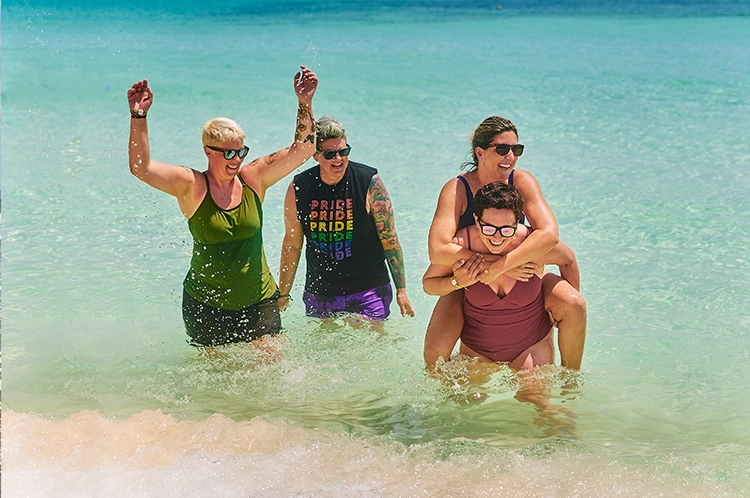 group of lgbtq women playing in the water in the ocean