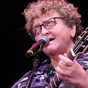 Dianne Davidson playing her guitar and singing