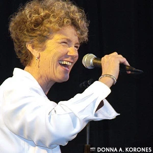 Margie Adam singing with a mic in her hand