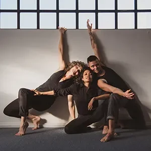 3 dancers crouching and arms interlaced
